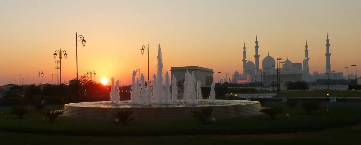 The mosque on the skyline at sunset behind a fountain