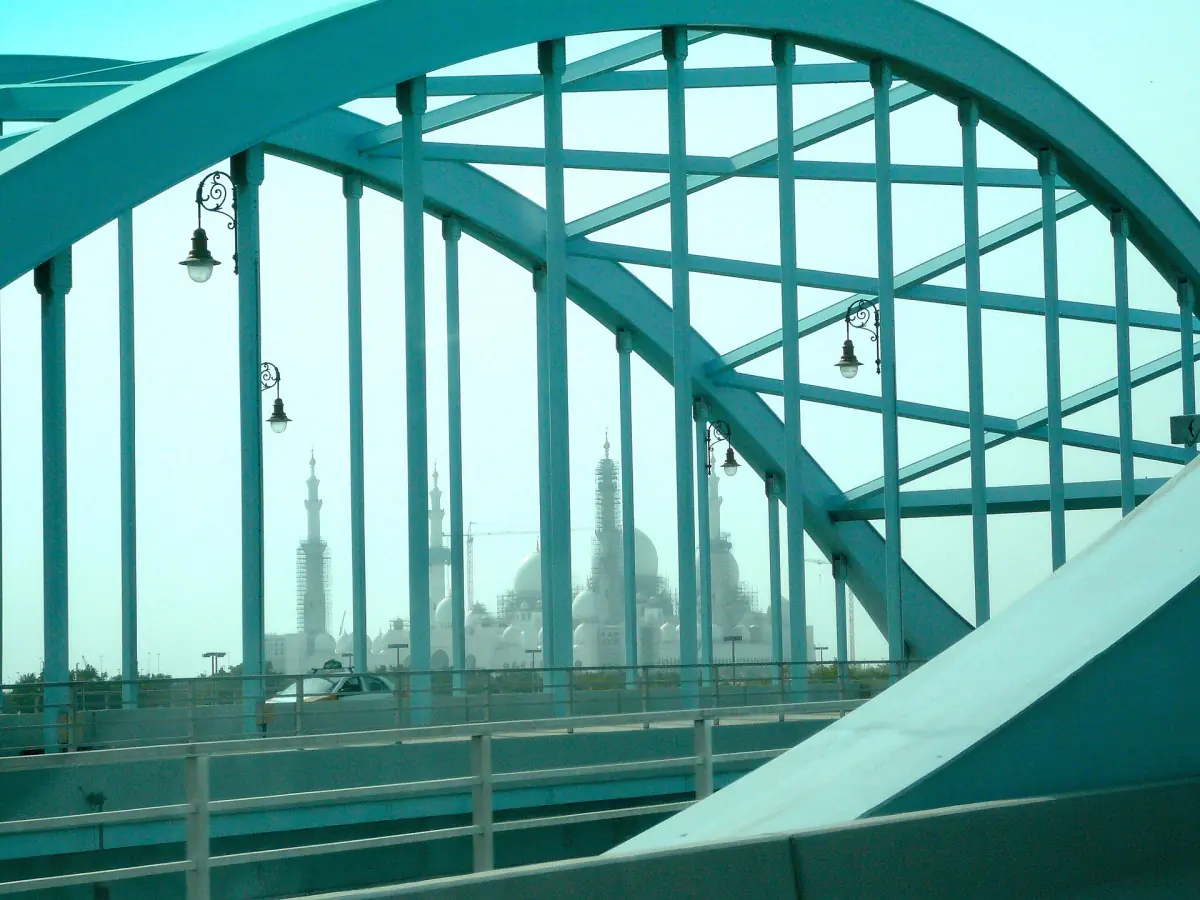 The mosque seen through the steel arches of a bridge